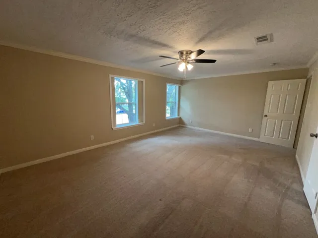 an empty room with windows and fan