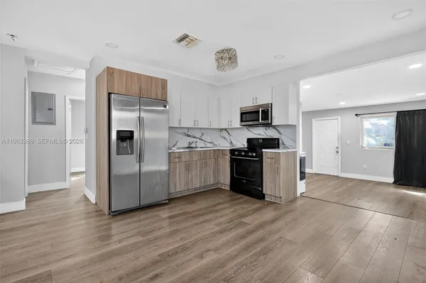 a kitchen with granite countertop a refrigerator and a stove top oven