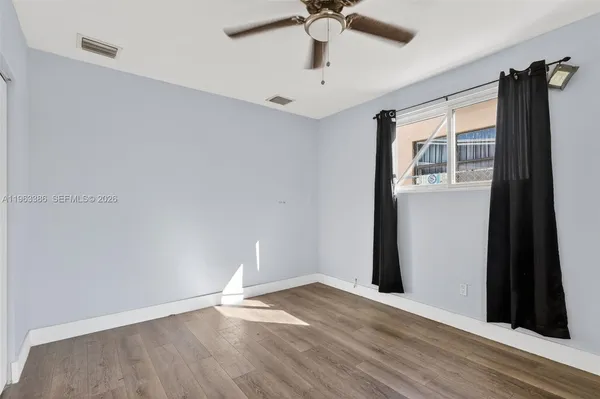 a view of an empty room with window and wooden floor