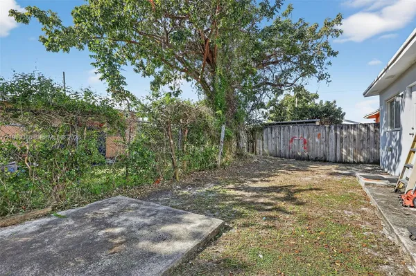 a view of a backyard with large trees and wooden fence