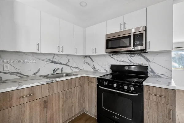 a kitchen with stainless steel appliances a stove a microwave a sink and cabinets