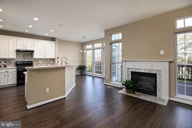 a living room with stainless steel appliances granite countertop a fireplace a flat screen tv and a fireplace