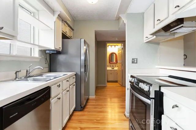 a kitchen with stainless steel appliances a sink a refrigerator and cabinets