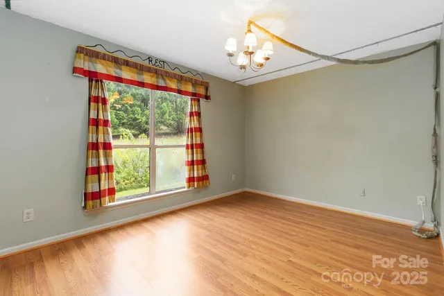 a view of empty room with window and wooden floor