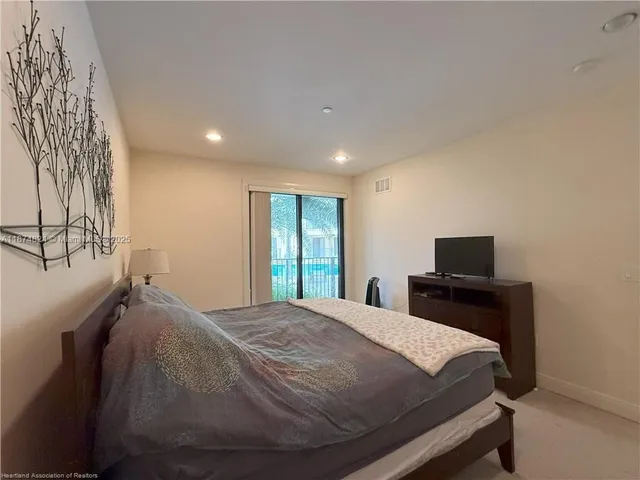 a bed sitting in a spacious bedroom next to a window and a flat screen tv