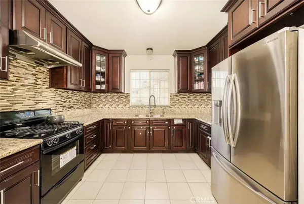 a kitchen with stainless steel appliances granite countertop a refrigerator a stove and a sink