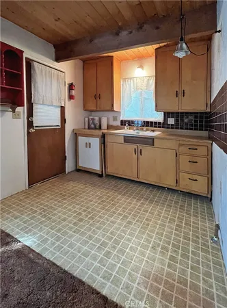 a kitchen with a stove a sink a window and cabinets