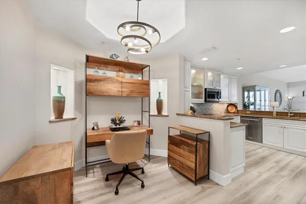 a kitchen with stainless steel appliances granite countertop a stove top oven a sink dishwasher a dining table and chairs with wooden floor
