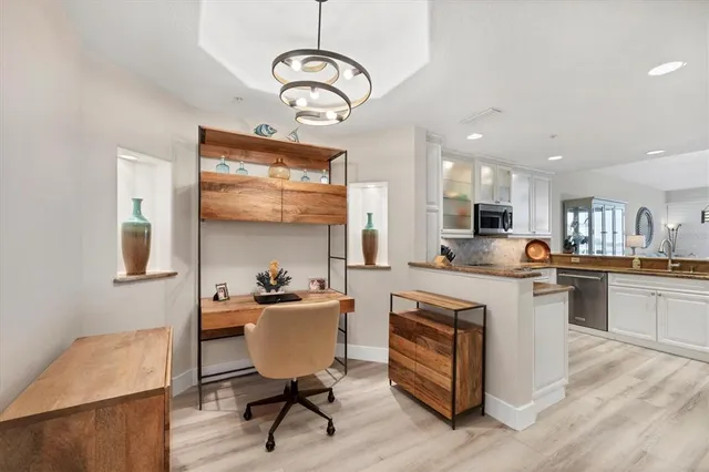 a kitchen with stainless steel appliances granite countertop a stove top oven a sink dishwasher a dining table and chairs with wooden floor