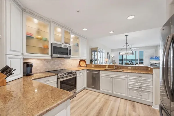 a kitchen with stainless steel appliances granite countertop a sink and stove top oven with wooden floor