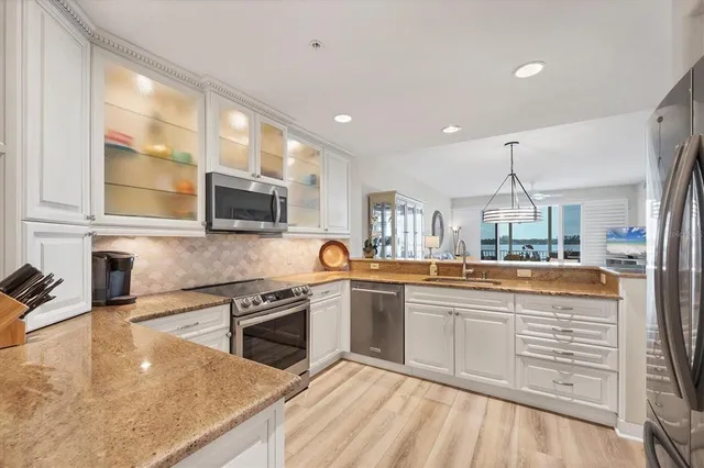 a kitchen with stainless steel appliances granite countertop a sink and stove top oven with wooden floor