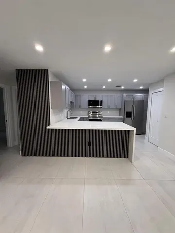 a large kitchen with a large counter top stainless steel appliances and cabinets