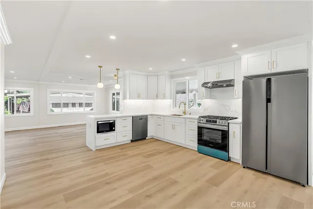 a large kitchen with stainless steel appliances a large counter top and a refrigerator