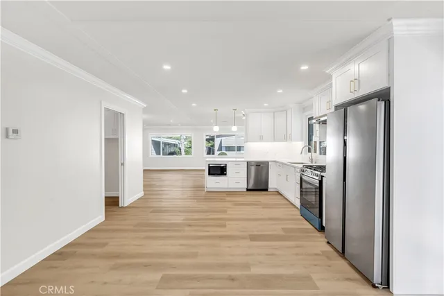 a large kitchen with kitchen island a stove a refrigerator a sink and a oven with wooden floor