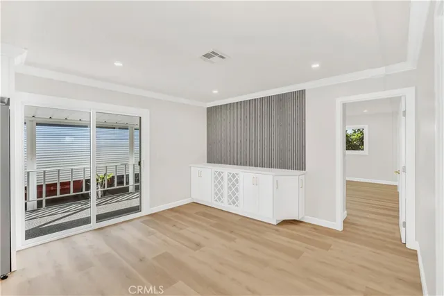 a view of an empty room with wooden floor and windows
