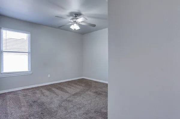 en empty room with windows and chandelier fan