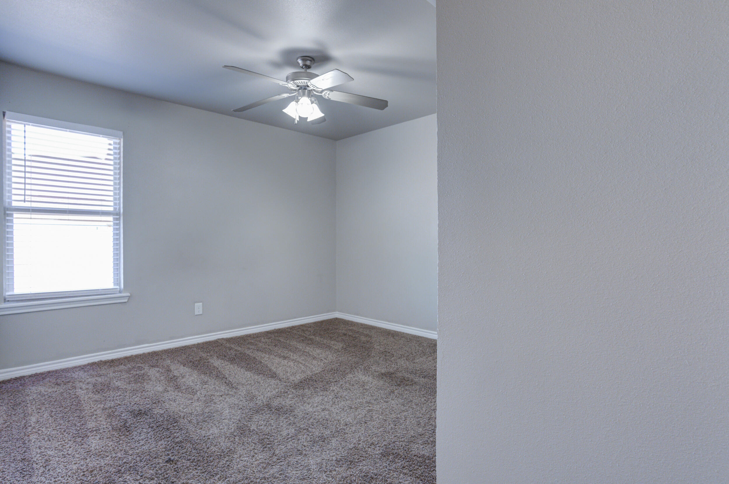 2022 88th Street Lubbock, TX 79423 - Photo 21 of 33 en empty room with windows and chandelier fan