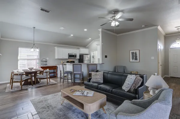 a living room with furniture kitchen view and a chandelier