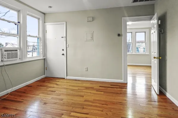 an empty room with wooden floor and windows