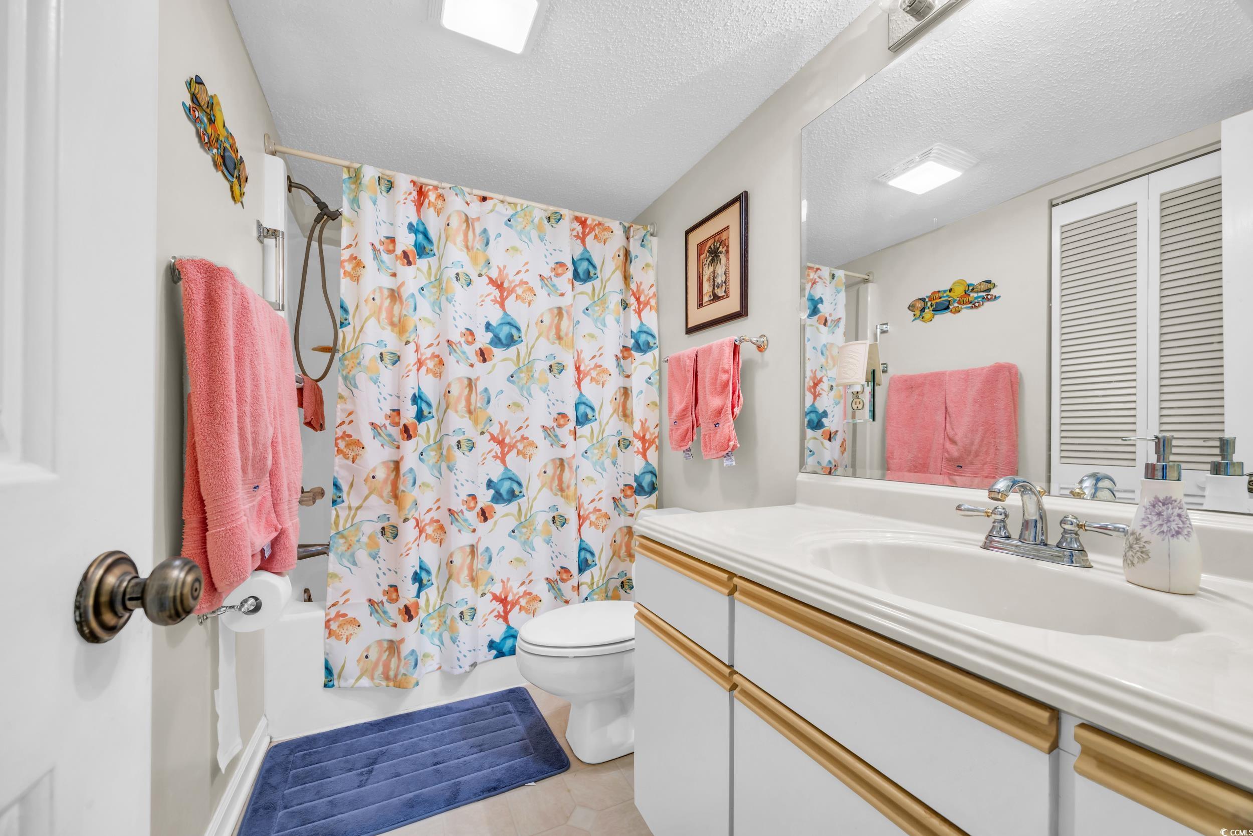 310 73rd Avenue North, Unit 5C Myrtle Beach, SC 29572 - Photo 14 of 20 Bathroom featuring shower / tub combo with curtain, a textured ceiling, vanity, and light tile patterned floors