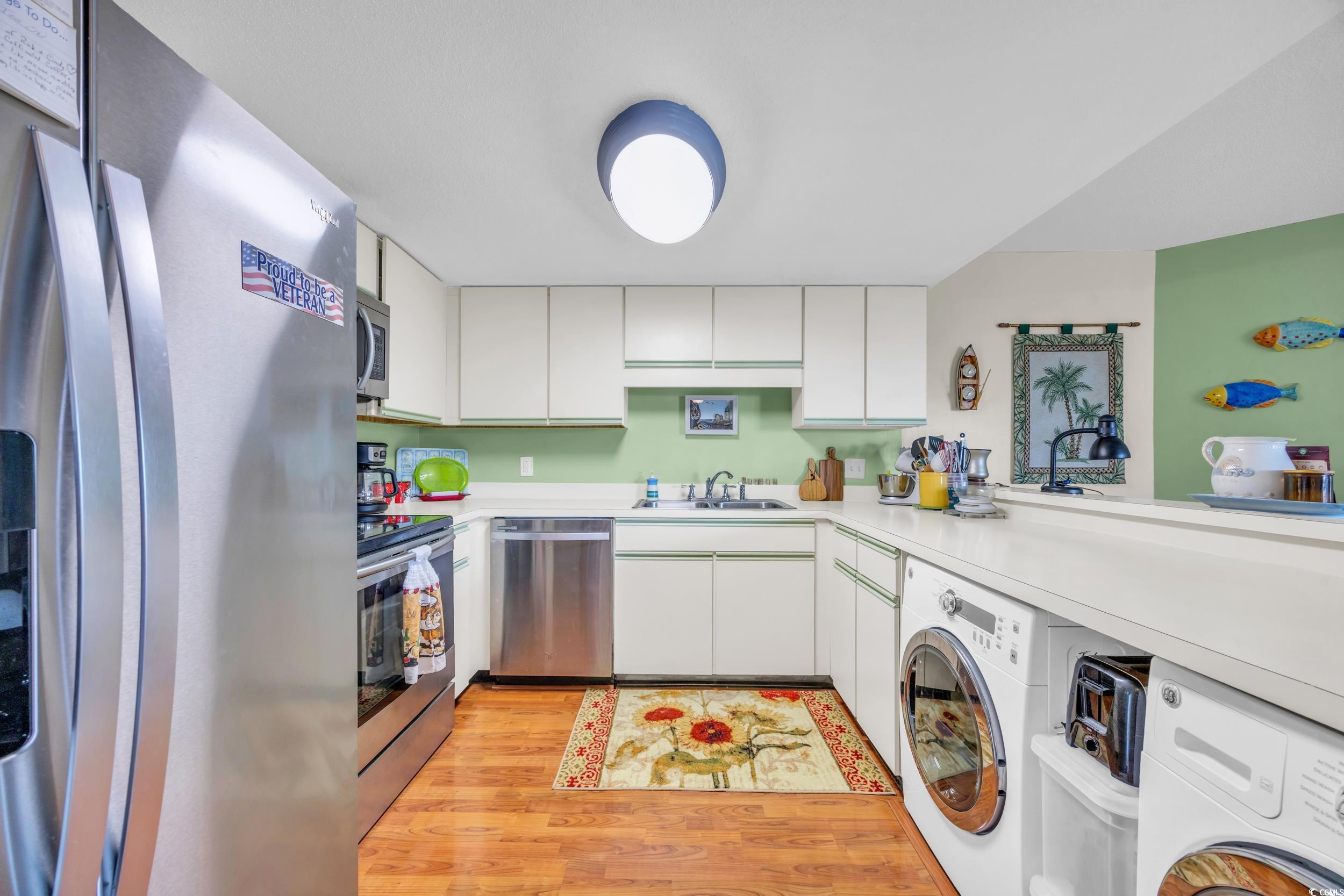310 73rd Avenue North, Unit 5C Myrtle Beach, SC 29572 - Photo 8 of 20 Kitchen featuring appliances with stainless steel finishes, light countertops, white cabinetry, and light wood-type flooring