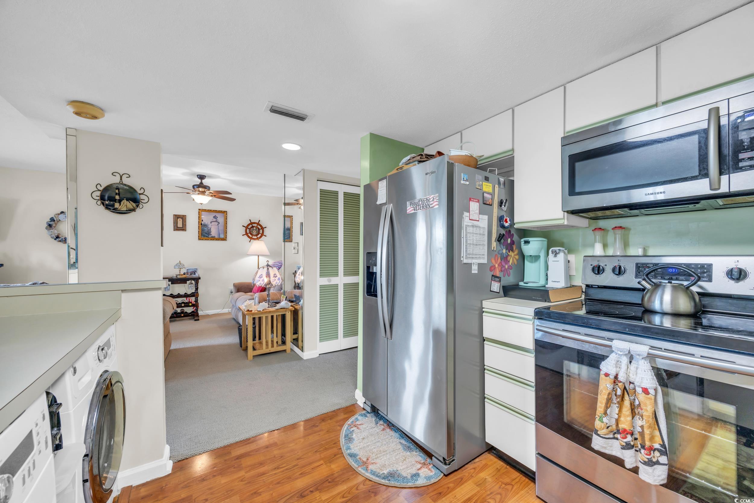 310 73rd Avenue North, Unit 5C Myrtle Beach, SC 29572 - Photo 9 of 20 Kitchen featuring appliances with stainless steel finishes, white cabinets, light countertops, light wood-style floors, and washer / clothes dryer
