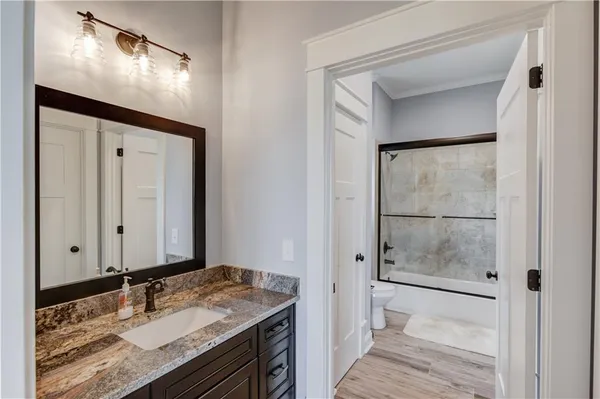 a kitchen with a sink dishwasher a stove and white cabinets with wooden floor