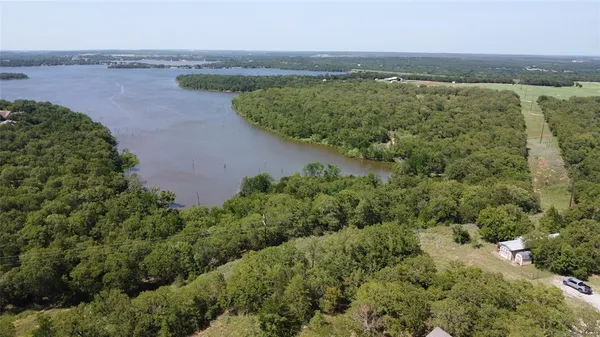 an aerial view of a houses with outdoor space and trees all around