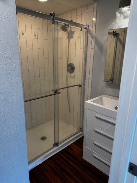 2018 West Rundberg Lane, Unit 6C Austin, TX 78758 - Photo 27 of 29 Bathroom with a textured wall, vanity, dark wood-style floors, and a shower stall