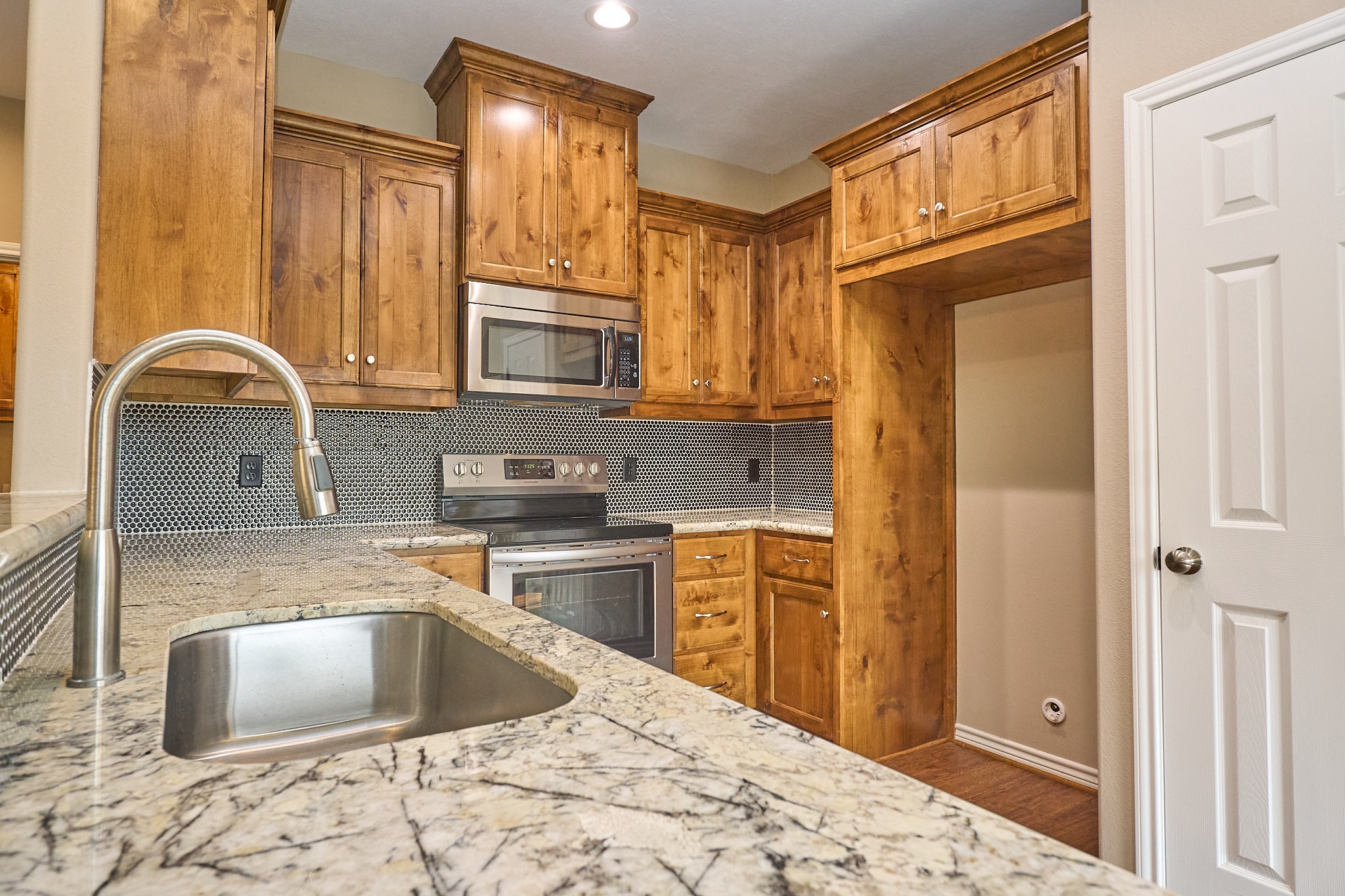 1807 Nuches Lane Bryan, TX 77803 - Photo 10 of 27 This kitchen features granite countertops, a sleek undermount sink, and stainless steel appliances. The warm wooden cabinetry provides ample storage, complemented by a modern tile backsplash.