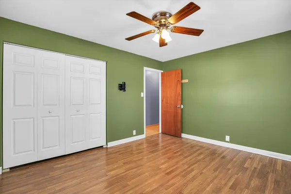 an empty room with wooden floor closet and fan