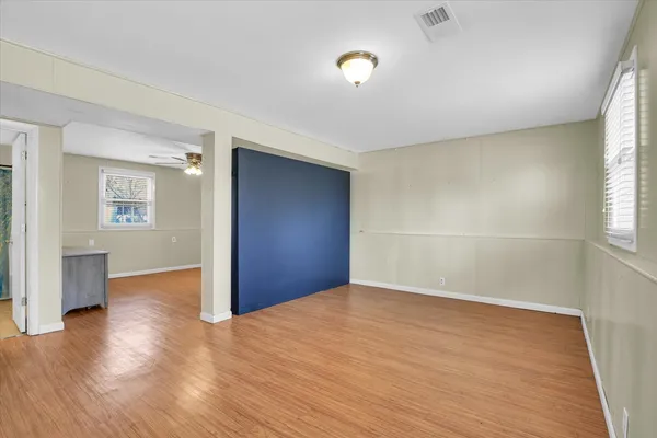 an empty room with wooden floor and windows