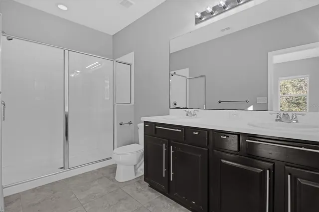 a bathroom with a sink a toilet a mirror and a shower