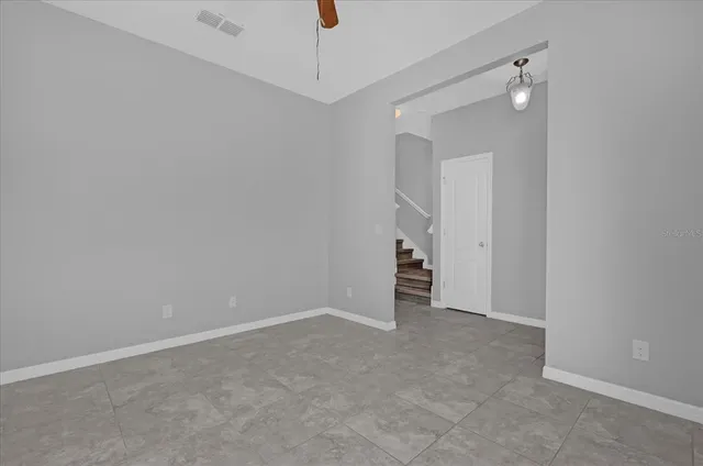 an empty room with an entryway and chandelier fan