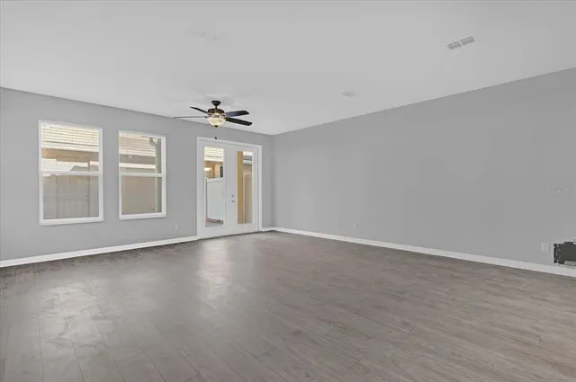 a view of an empty room with a window and wooden floor