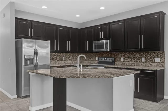 a kitchen with stainless steel appliances granite countertop a stove a sink and a microwave