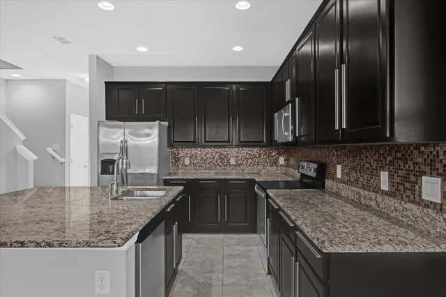 a kitchen with kitchen island granite countertop stainless steel appliances a sink stove and cabinets