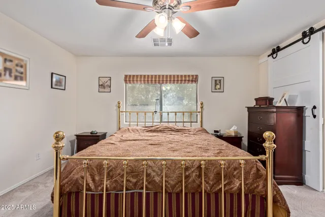 a bedroom with a bed a dresser and a chandelier