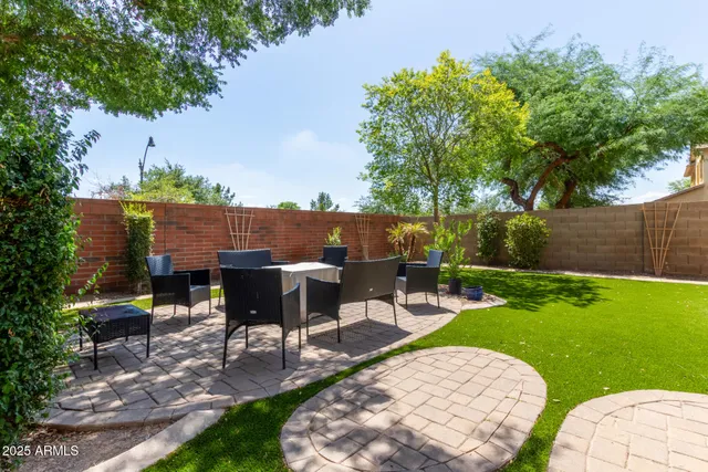 a view of a patio with table and chairs potted plants and a large tree