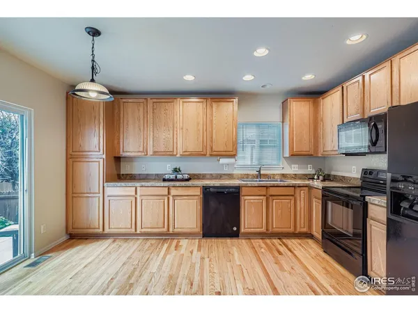a kitchen with stainless steel appliances granite countertop a refrigerator a sink dishwasher a oven with white cabinets and wooden floor