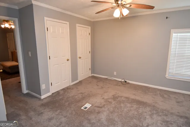 an empty room with windows and a chandelier fan