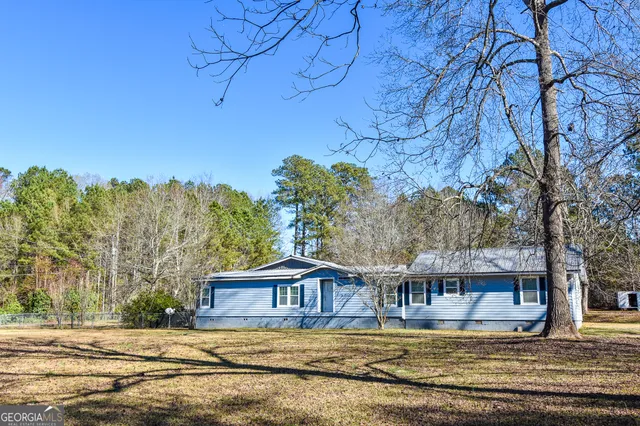 a view of a house with large trees and wooden fence