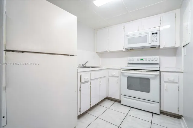 a kitchen with white cabinets and white appliances
