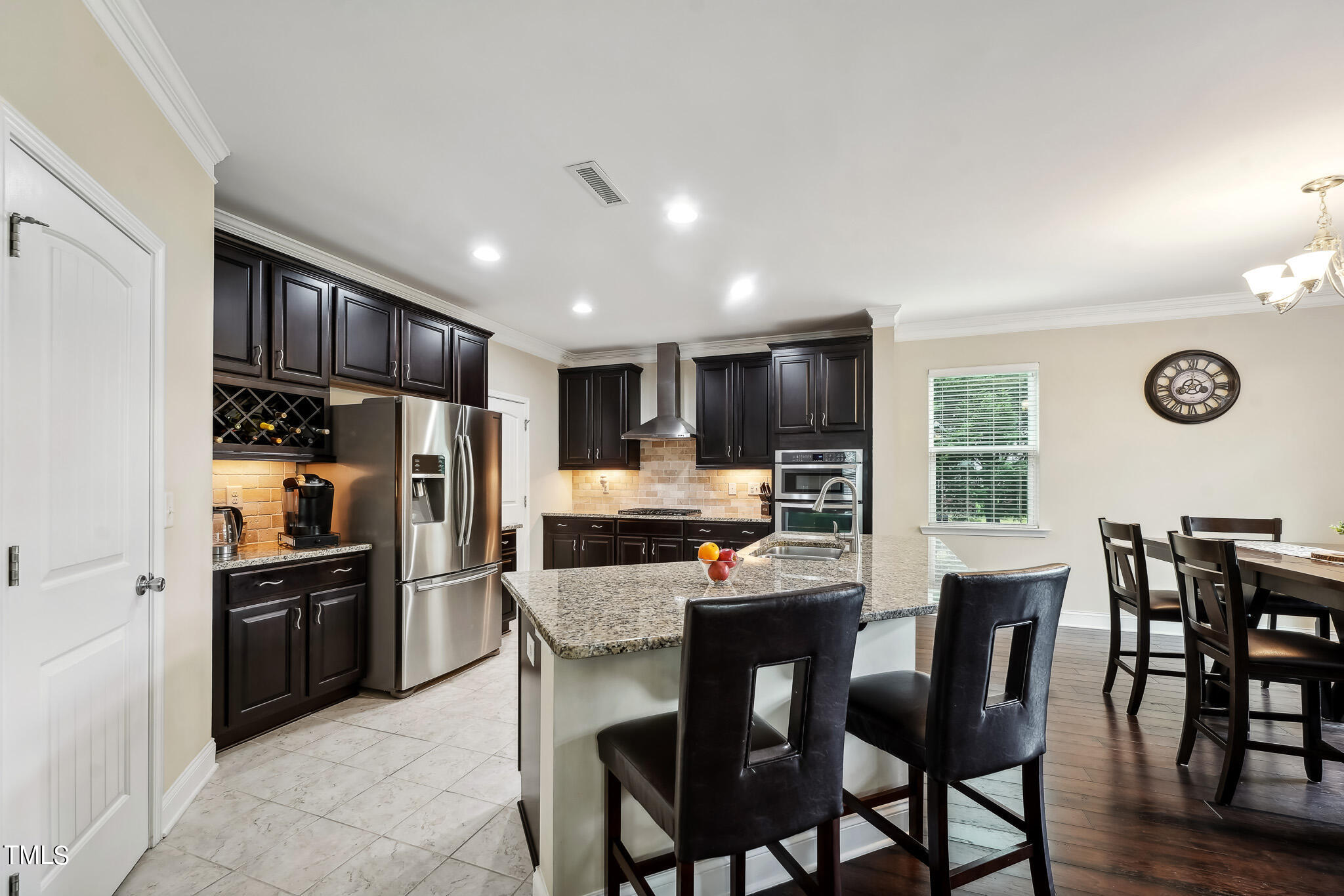 5608 Spring Glen Lane Raleigh, NC 27616 - Photo 10 of 30 a kitchen with stainless steel appliances kitchen island granite countertop a refrigerator a stove a dining table and chairs with wooden floor