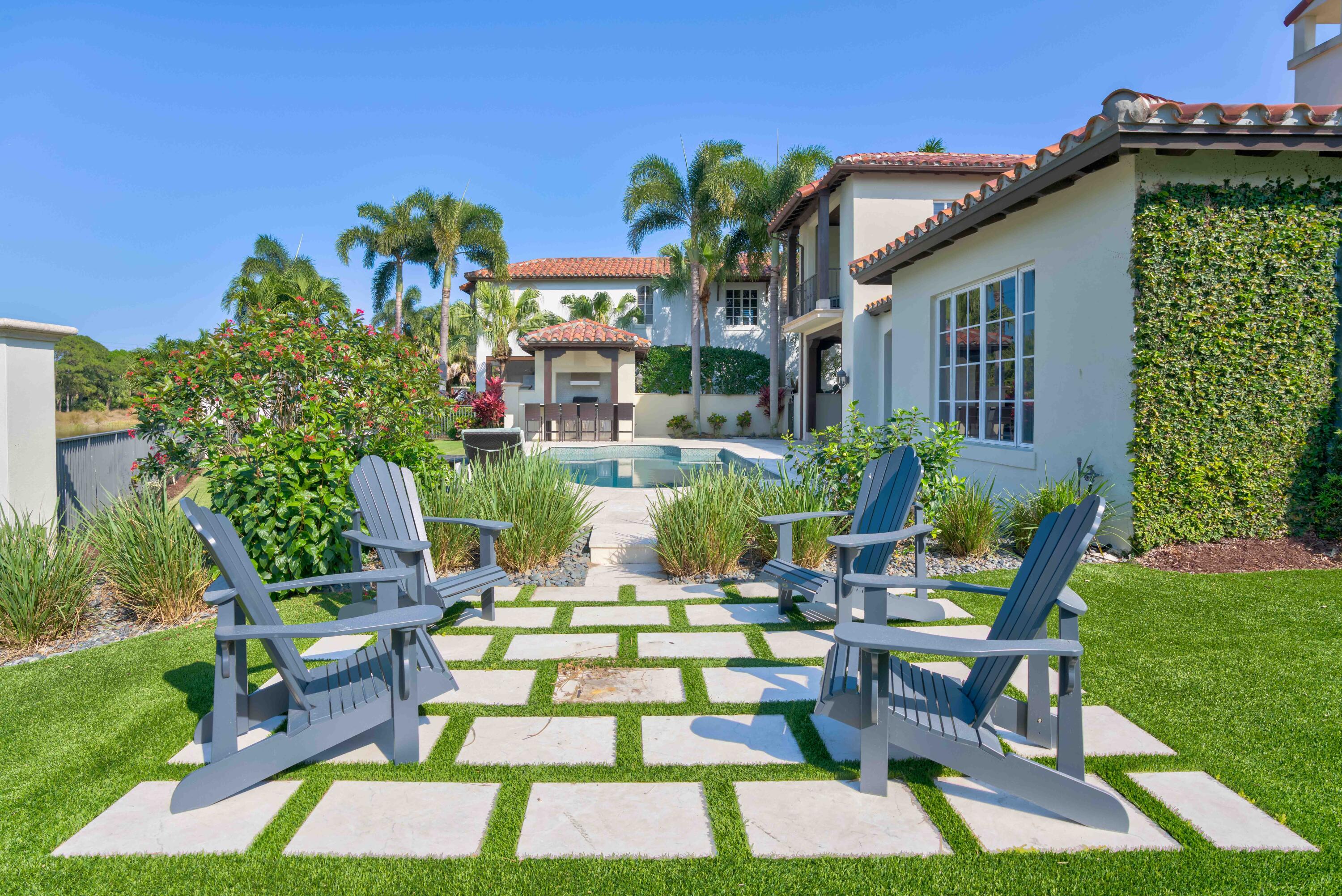 444 Red Hawk Drive Jupiter, FL 33477 - Photo 49 of 58 a view of a chair and tables in the backyard of the house