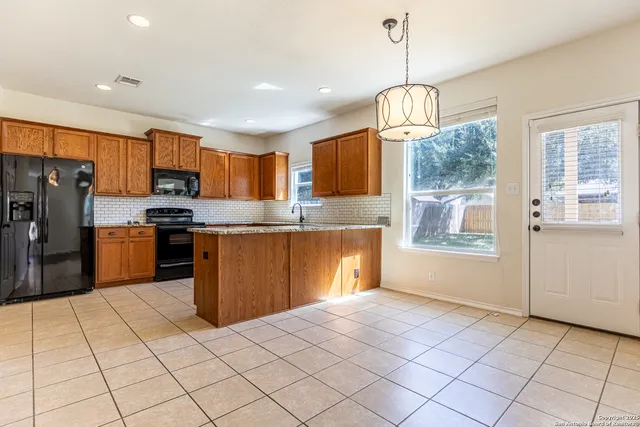 a kitchen with stainless steel appliances granite countertop a refrigerator a sink a stove top oven a counter space and cabinets