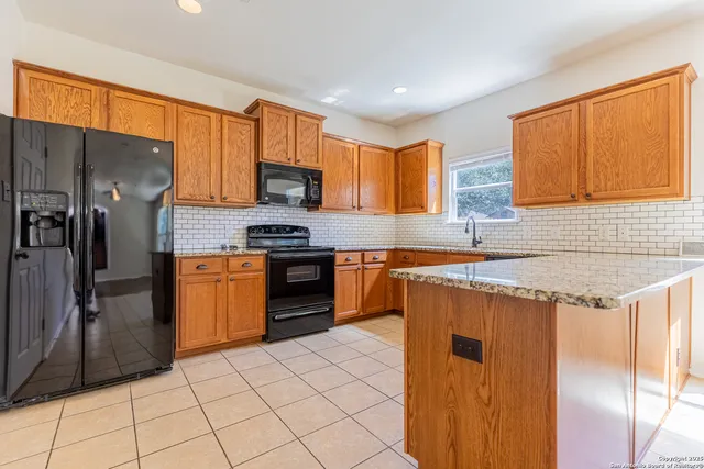 a kitchen with stainless steel appliances granite countertop a refrigerator a stove and a sink