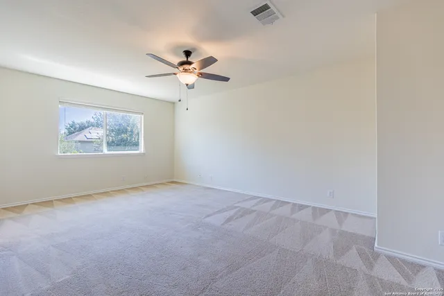 an empty room with windows and fan
