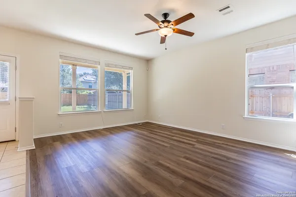 a view of an empty room with a window and wooden floor