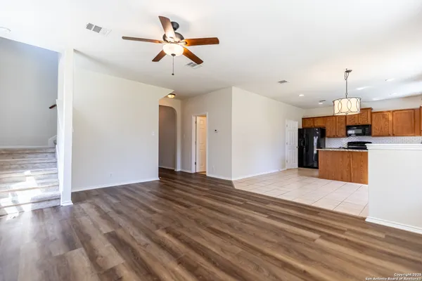 a view of empty room with wooden floor and ceiling fan